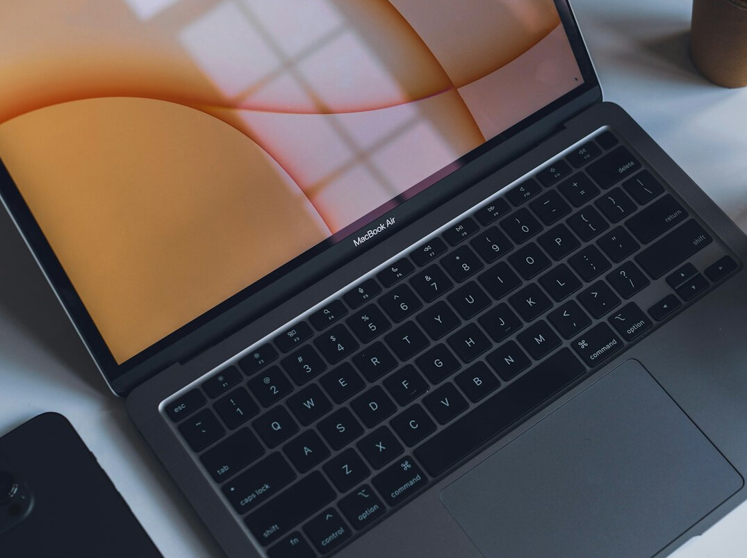 Laptop with notebook and coffee cup on a minimalist desk